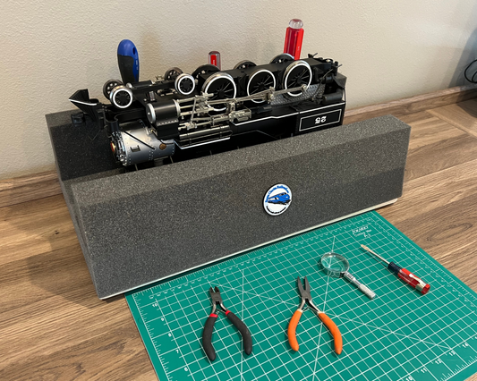 Model train engine on a foam cradle stand with tools