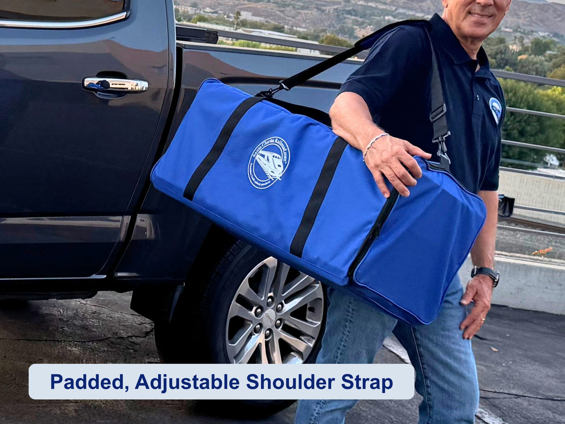 Man carrying the Pro Pak Carrying Case on its padded shoulder strap beside a pickup truck