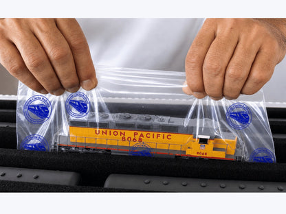 Hands lifting a Union Pacific HO diesel on a Short Pro Pak Easy-Lift Sheet