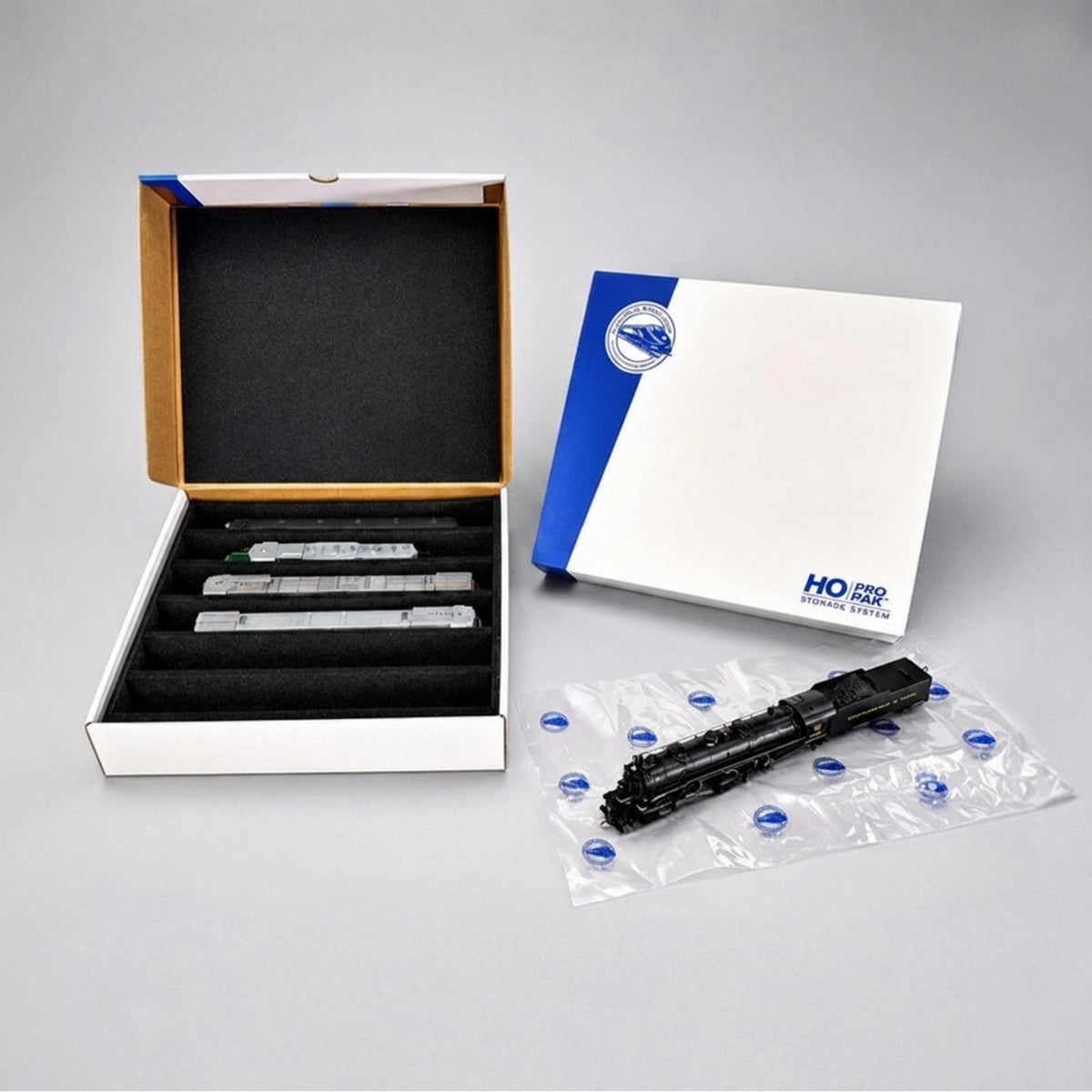 Pro Pak HO Compact box open beside its lid, with a steam locomotive on an Easy-Lift Sheet